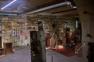 Ein Raum mit Steinwänden, mehreren Kartons, einem roten Teppich und einem Spiegel.