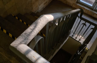 Treppenhaus mit einem Geländer, das von Sonnenlicht beleuchtet wird.