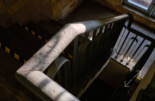 Treppenhaus mit einem Geländer, das von Sonnenlicht beleuchtet wird.